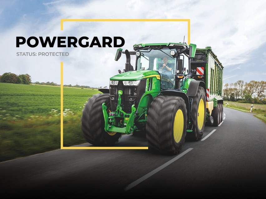 Ciągnik John Deere 7R z przyczepą na drodze w żółtej ramce PowerGard